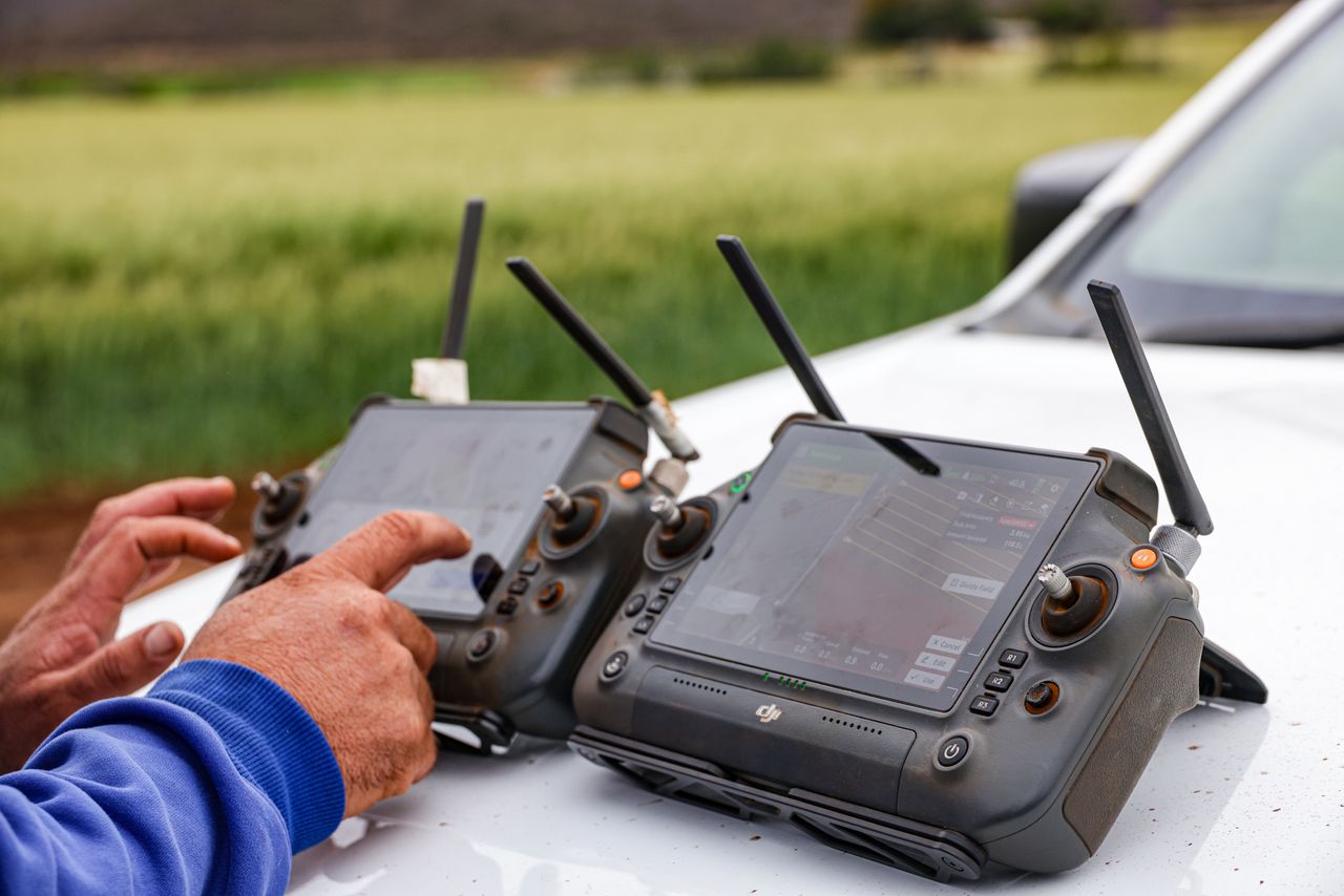 our-experience Close-up of farmers using drone controllers on a farm for precision agriculture.
